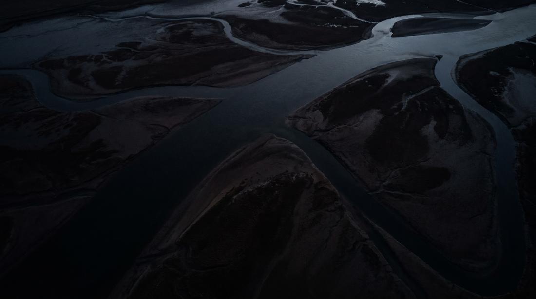 A river seen from above, winding through dark country